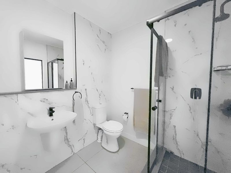Modern bathroom featuring marble-look wall tiles, a pedestal basin, and a walk-in shower with a glass screen.