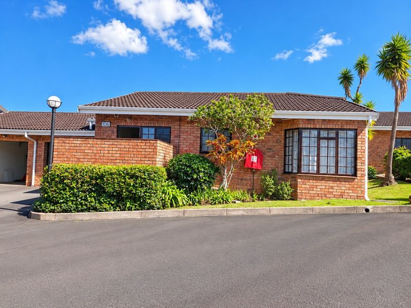 Front elevation of a brick townhouse featuring a bay window, tiled roof, and well-maintained garden area with driveway access.