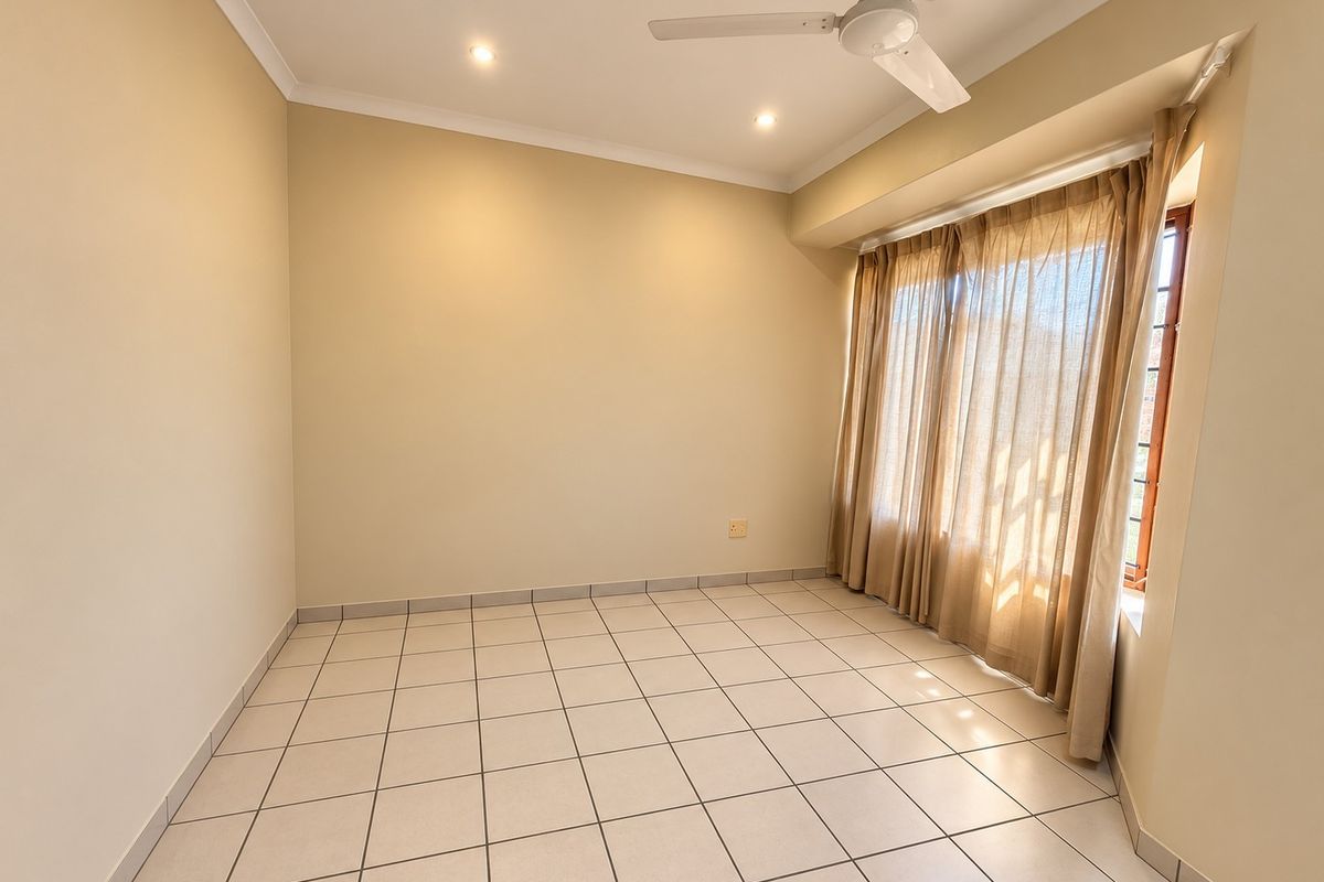 A bright, empty bedroom featuring neutral tiled flooring, a ceiling fan, and recessed lighting, ready for personalization.