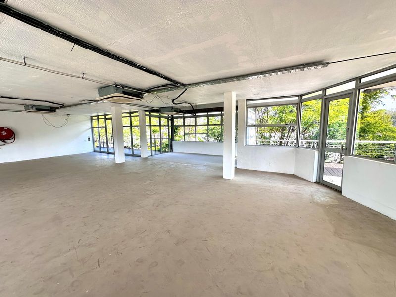 Spacious open-plan office area featuring large windows, exposed ceiling infrastructure, and direct access to a balcony, offering a blank canvas for custom fit-out.
