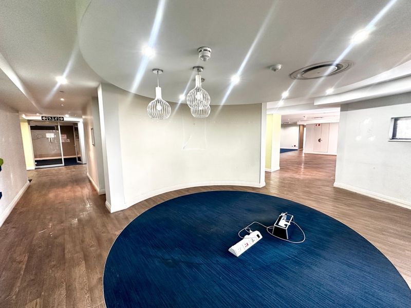 A bright, modern office space featuring a curved feature wall, recessed lighting, and durable laminate flooring, offering a clean and professional environment.