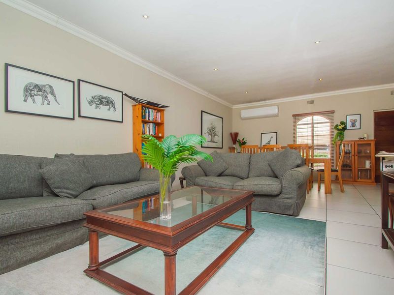 Spacious open-plan living and dining area featuring tiled flooring, recessed downlighting, and a wall-mounted air conditioning unit.