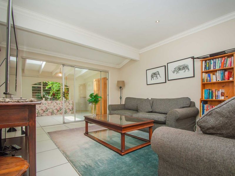 A comfortable living room featuring tiled flooring, crown molding, and large sliding glass doors that provide natural light and access to an adjacent space.