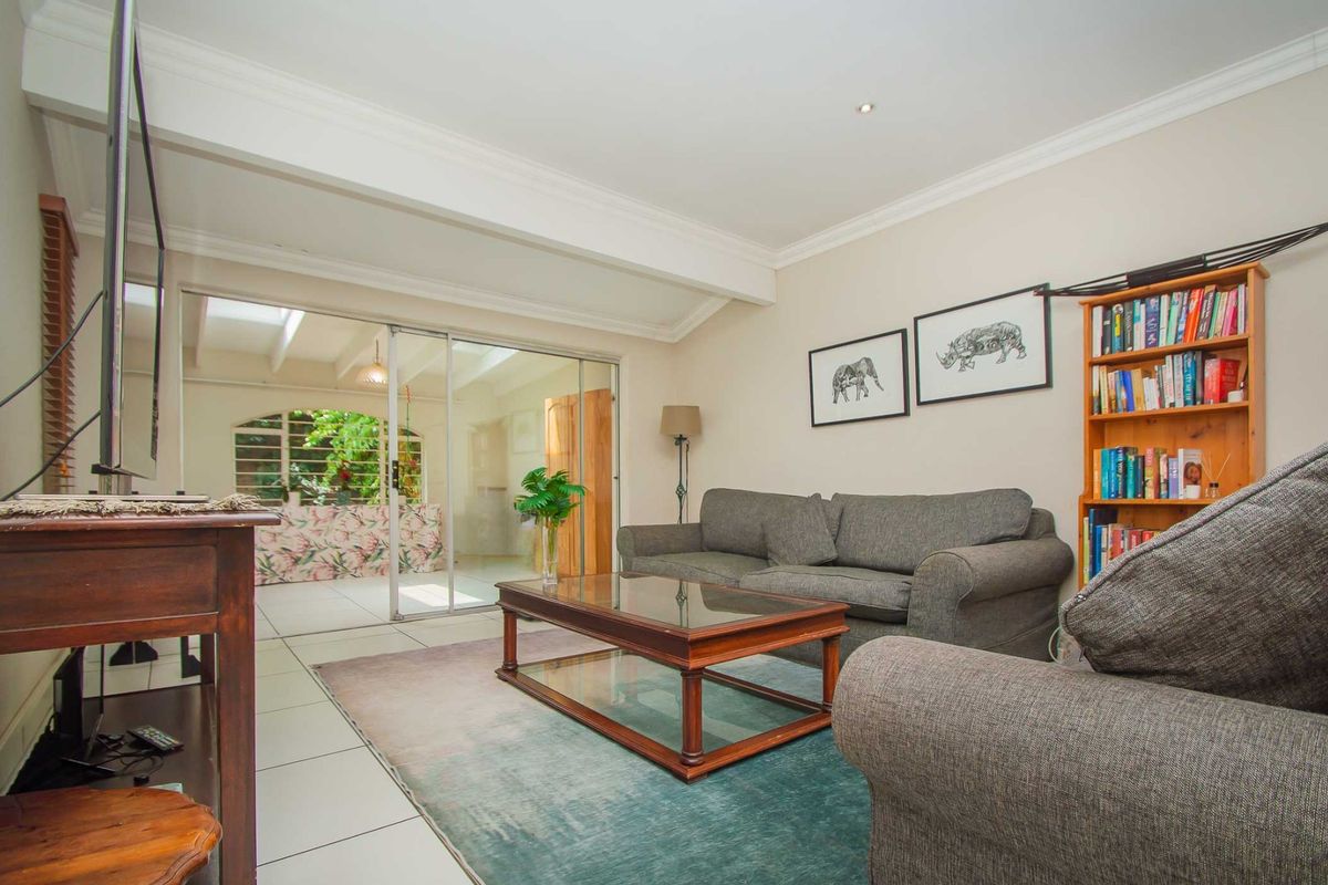 A comfortable living room featuring tiled flooring, crown molding, and large sliding glass doors that provide natural light and access to an adjacent space.