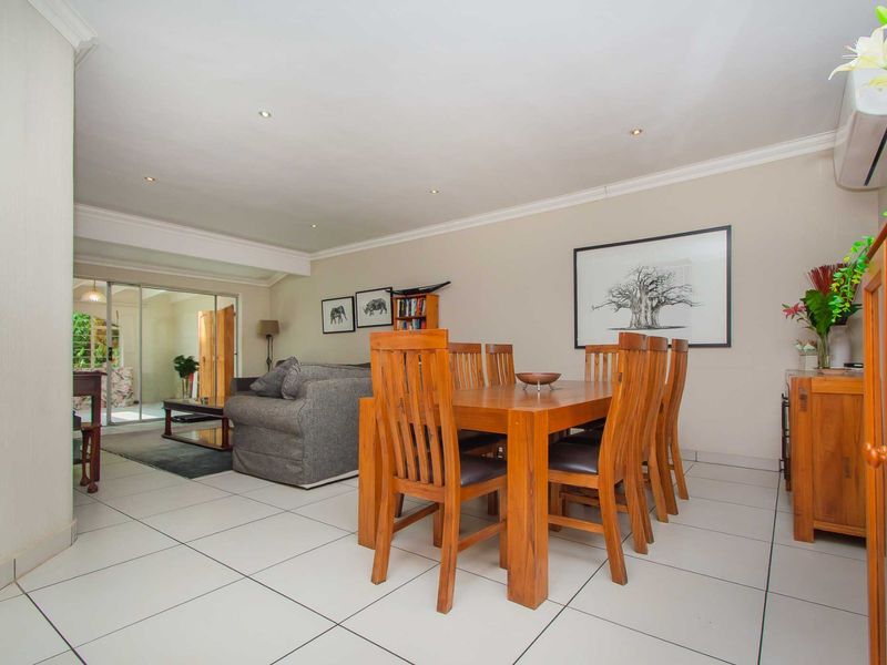 Spacious open-plan living and dining area featuring neutral tiled flooring, recessed lighting, and sliding glass doors leading to an outdoor space.