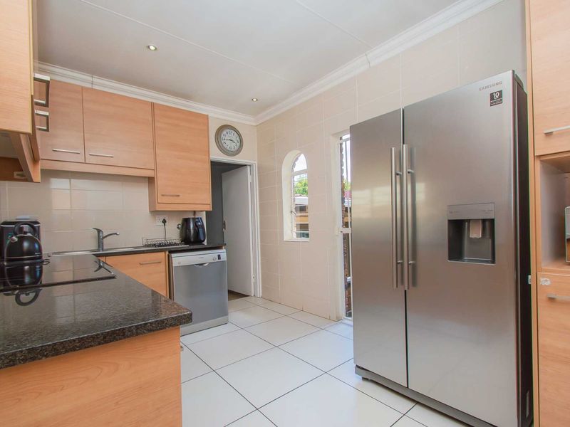 Functional kitchen featuring light wood cabinetry, granite countertops, tiled flooring, and a dedicated space for a large refrigerator.