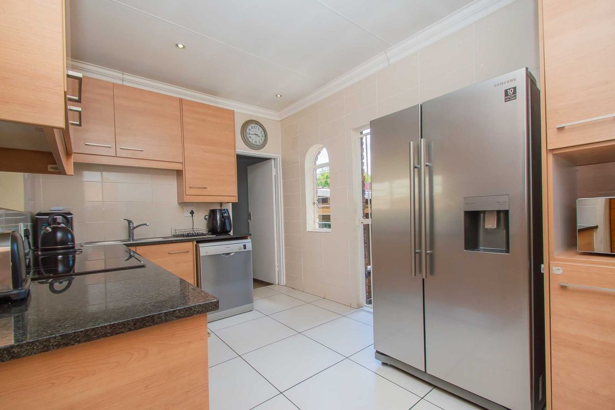 Functional kitchen featuring light wood cabinetry, granite countertops, tiled flooring, and a dedicated space for a large refrigerator.