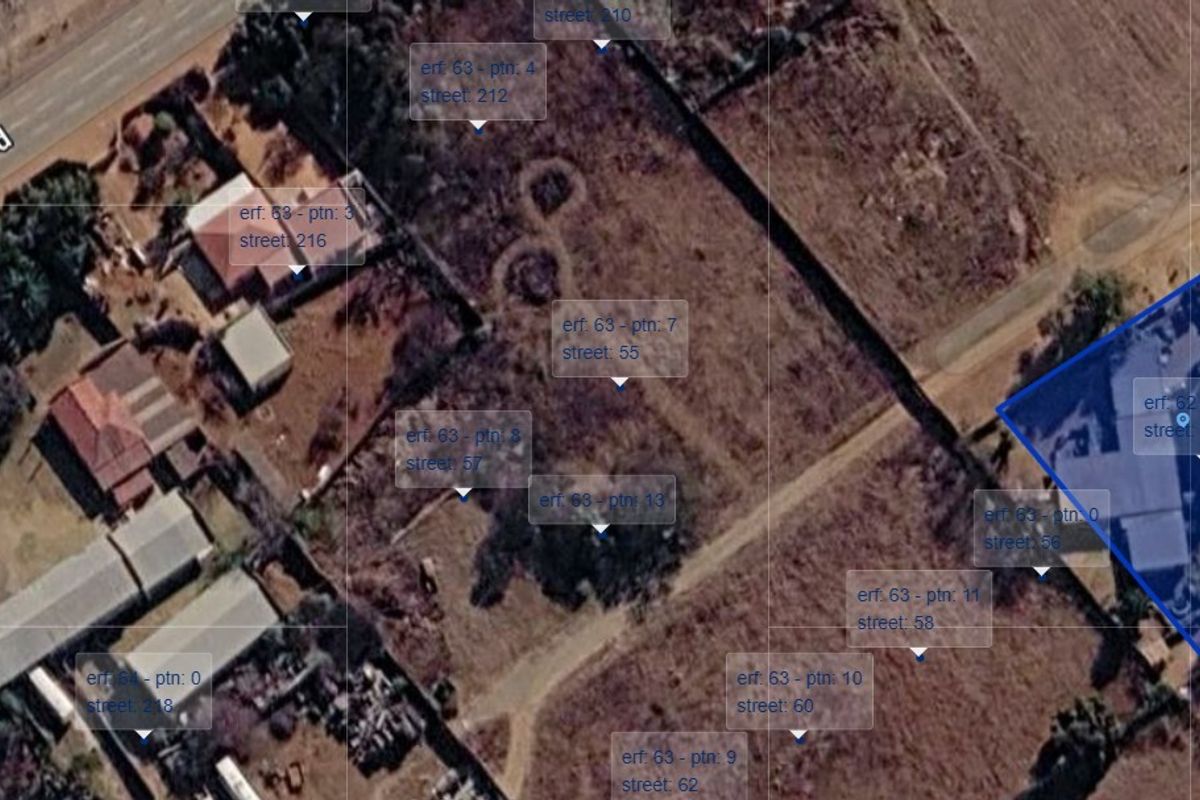 An aerial view of a vacant residential land plot showing surrounding properties and site boundaries.