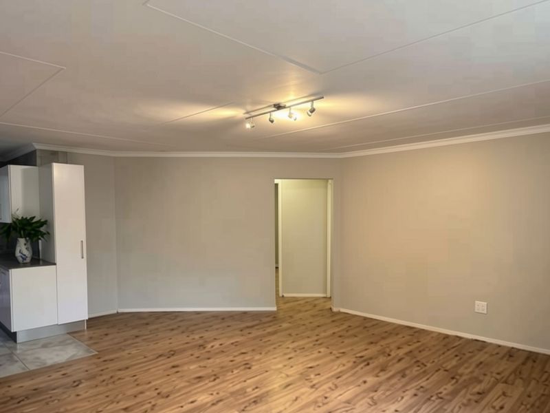 Spacious open-plan living area featuring modern laminate flooring, neutral wall tones, and integrated cabinetry, offering a versatile and well-maintained blank canvas.