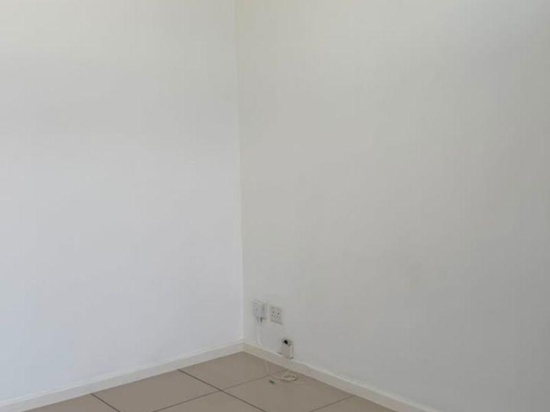 A clean, empty room featuring neutral tiled flooring and white walls, providing a versatile blank canvas for any living space.