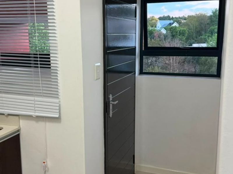 A clean, modern kitchen area featuring tiled flooring, dark cabinetry, and a window with views, presenting a bright and well-maintained space.