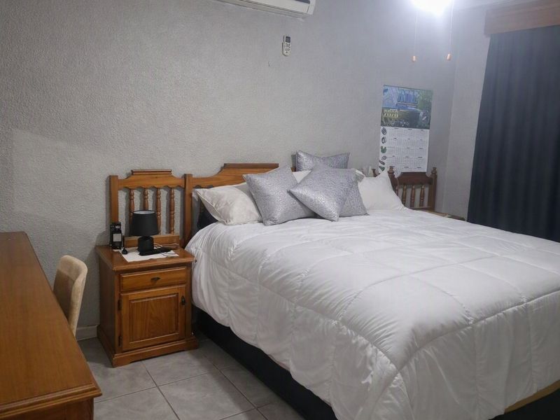 A functional bedroom featuring tiled flooring and a wall-mounted split-system air conditioning unit.
