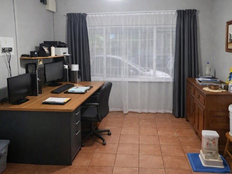 A functional home office space featuring tiled flooring and a large window, providing a practical area for work or study.