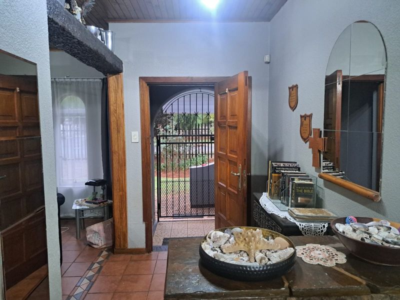 Entrance hall featuring tiled flooring, timber ceiling details, and a secure timber door leading to an outdoor area.