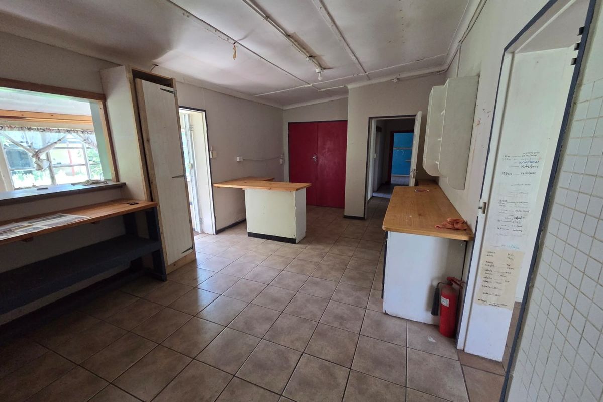 A vacant kitchen area featuring tiled flooring, built-in wooden countertops, and cabinetry, offering a blank canvas for renovation and modernization.