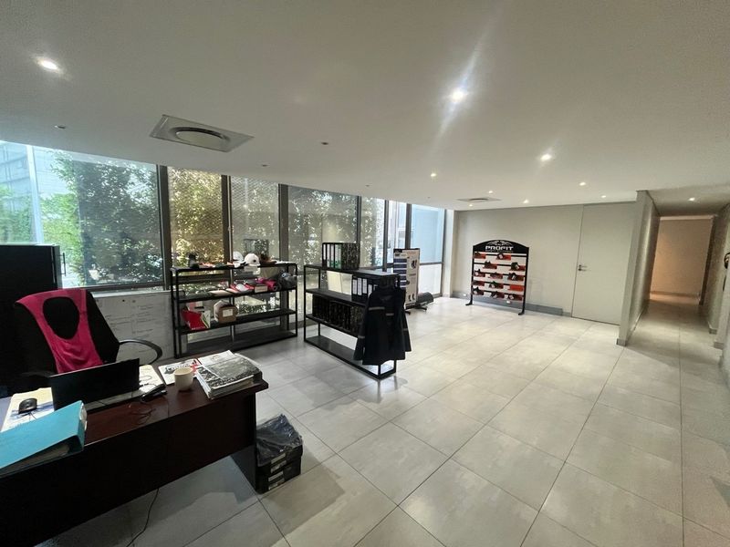A bright, modern office space featuring large floor-to-ceiling windows, neutral tiled flooring, and recessed ceiling lighting, suitable for a professional industrial or commercial environment.
