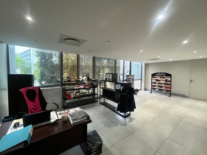 A bright, modern office space featuring large floor-to-ceiling windows, tiled flooring, and recessed downlighting, suitable for a professional industrial or commercial environment.