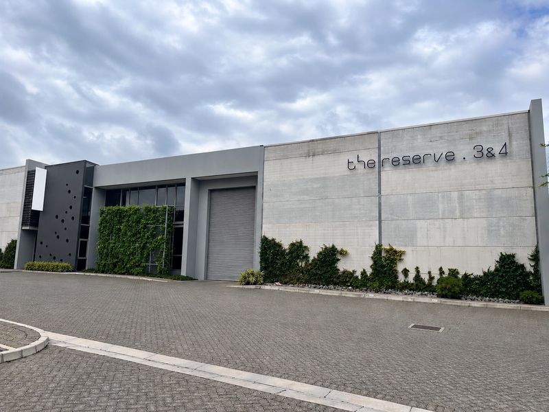 Modern industrial facade featuring a large roller shutter door, concrete finish, and integrated vertical garden elements at The Reserve units 3 and 4.