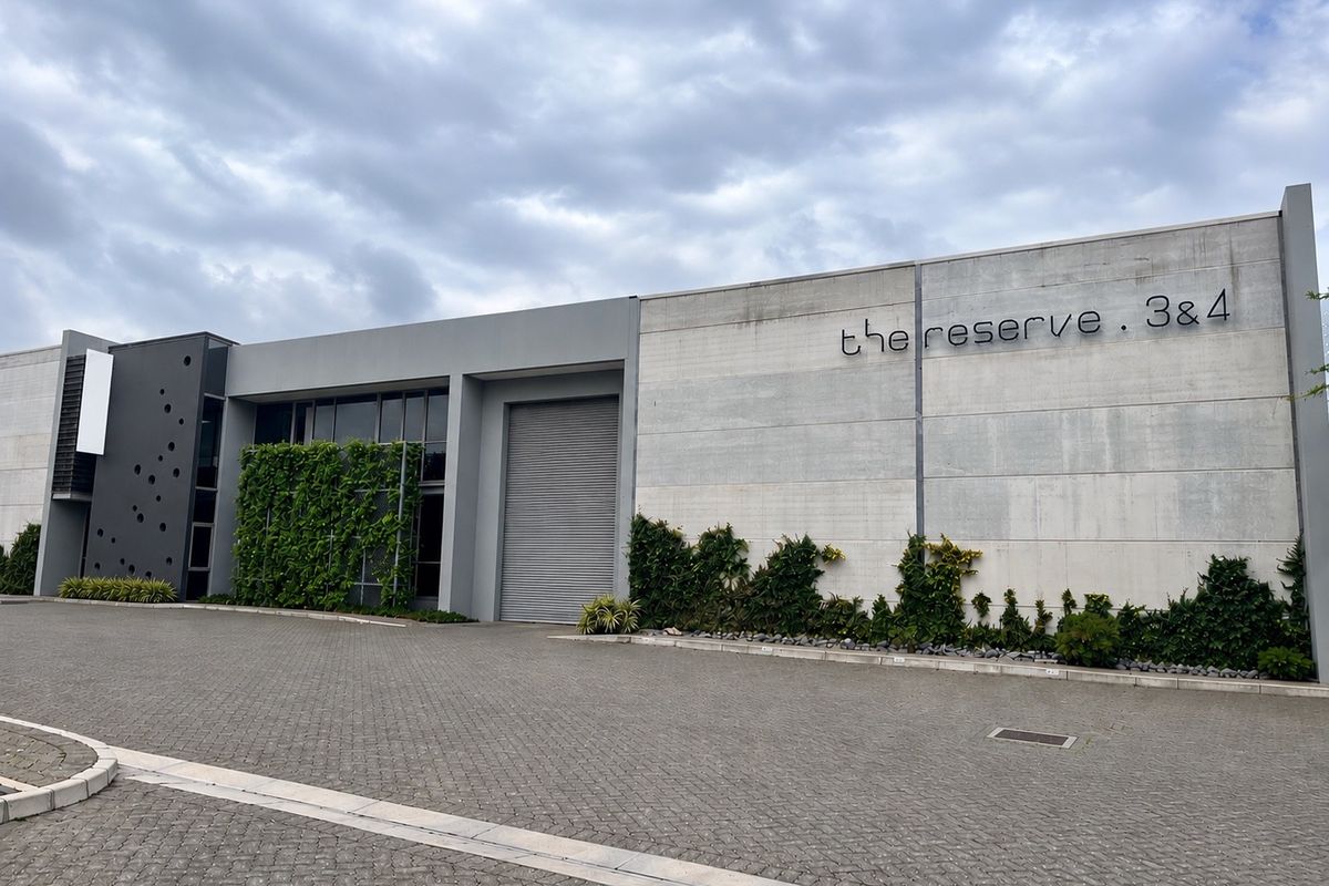 Modern industrial facade featuring a large roller shutter door, concrete finish, and integrated vertical garden elements at The Reserve units 3 and 4.