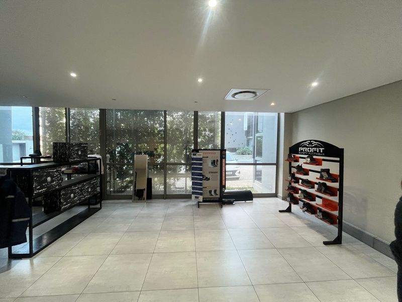 A bright, modern industrial entry area featuring large format floor tiles, recessed lighting, and expansive floor-to-ceiling windows providing natural light.