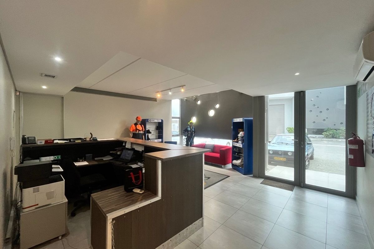 A functional industrial reception area featuring a built-in service desk, tiled flooring, and glass entrance doors providing natural light.