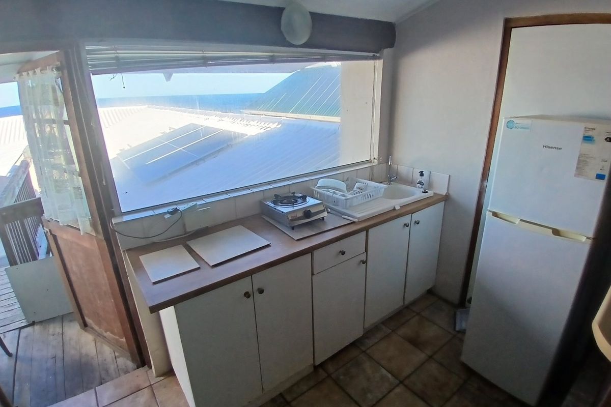 Compact kitchen area featuring built-in cabinetry, a sink, and tiled flooring, with direct access to an outdoor balcony area.