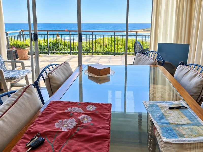 Dining area featuring large sliding glass doors that open onto a balcony with expansive ocean views.