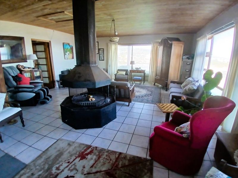 Spacious living room featuring a central freestanding fireplace, tiled flooring, and a timber-clad ceiling with large windows providing natural light.