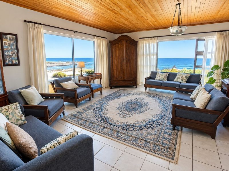Spacious living room featuring a timber-clad ceiling, tiled floors, and expansive sliding glass doors offering panoramic ocean views.