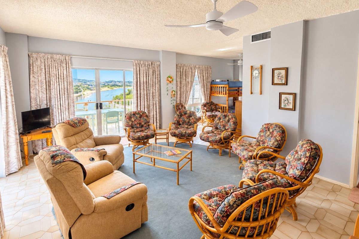 Spacious living area featuring tiled and carpeted flooring, ceiling fan, and large sliding glass doors providing natural light and access to the balcony.
