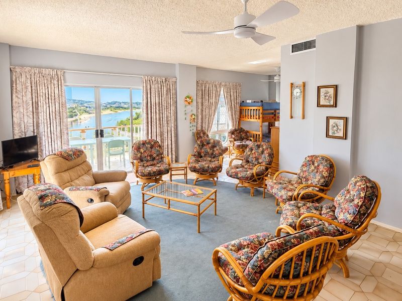 Spacious living area featuring tiled and carpeted flooring, ceiling fan, and large sliding glass doors providing natural light and access to the balcony.