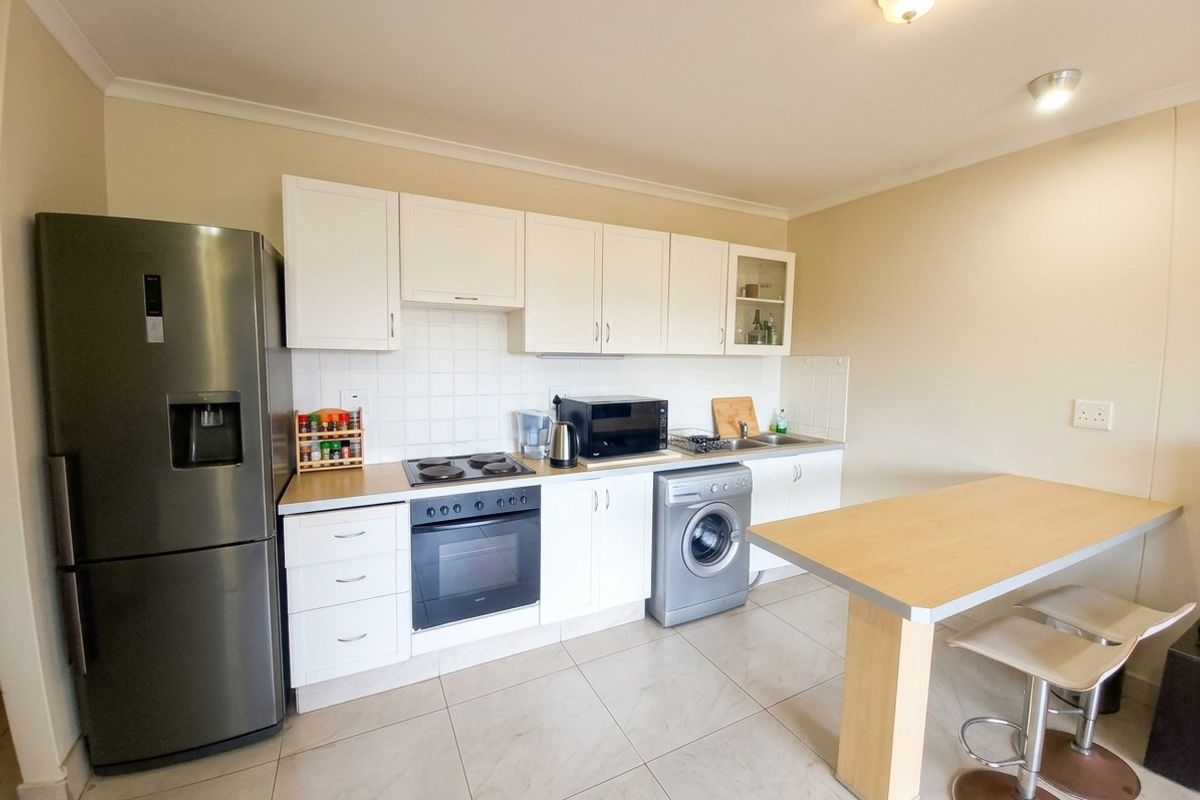 A functional kitchen featuring white cabinetry, tiled backsplash, built-in oven with hob, and tiled flooring, providing a practical workspace for daily cooking.