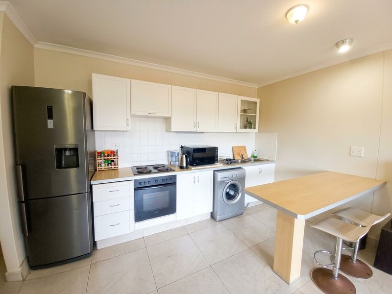 A functional kitchen featuring white cabinetry, tiled backsplash, built-in oven with hob, and tiled flooring, providing a practical workspace for daily cooking.