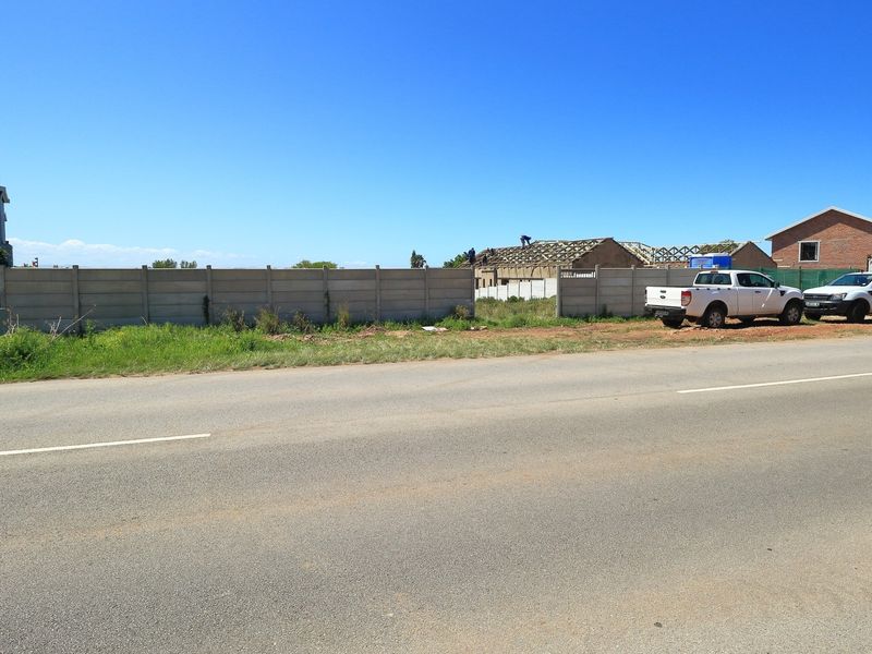 Street view of a vacant residential plot enclosed by a precast concrete boundary wall, situated in a developing neighborhood.