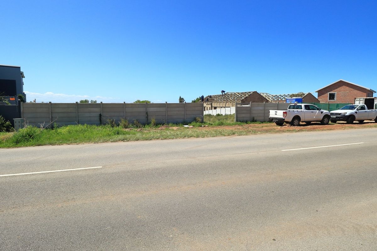 Street view of a vacant residential plot enclosed by a precast concrete boundary wall, situated in a developing neighborhood.