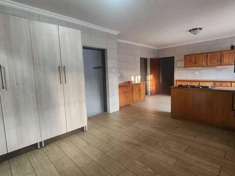 Spacious kitchen featuring tiled flooring, wall tiling, and a central island with a built-in hob, offering a functional layout with ample storage cabinetry.