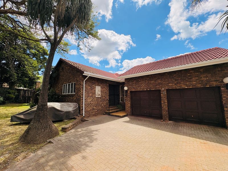 Front view of a face brick house featuring a double garage, tiled roof, and a paved driveway.