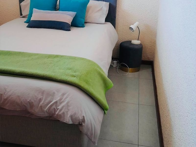 A compact bedroom featuring neutral tiled flooring and textured wall finishes, providing a functional space for rest.