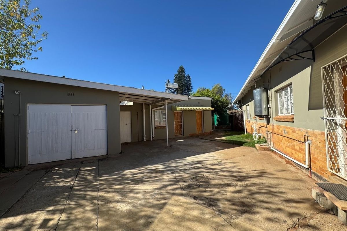Rear exterior view showing a concrete driveway, garage, and building facade with a solar water heating system.