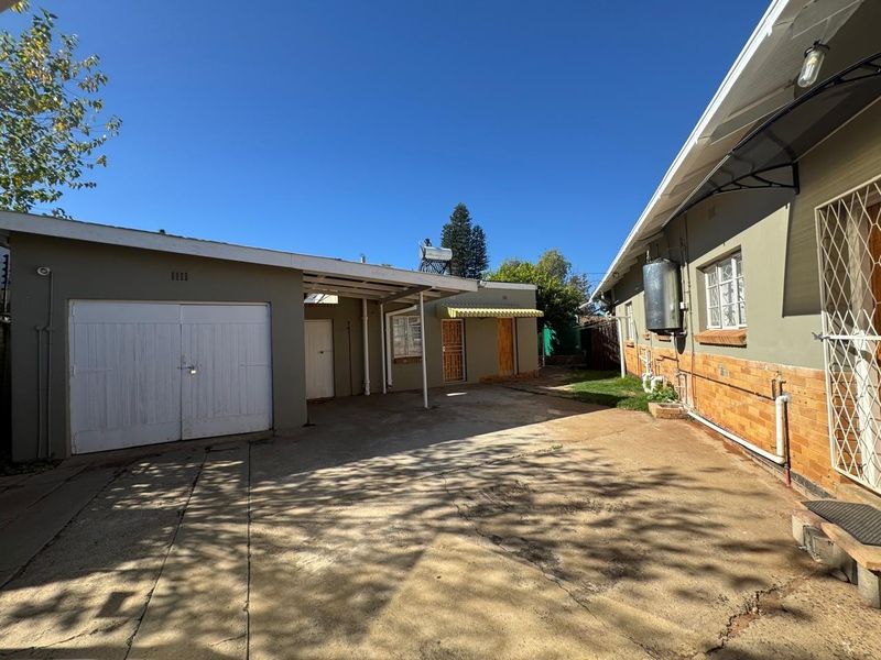 Rear exterior view showing a concrete driveway, garage, and building facade with a solar water heating system.