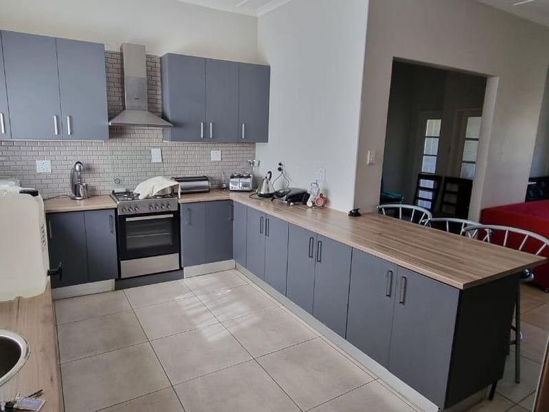 Modern kitchen featuring grey cabinetry, wood-look laminate countertops, subway tile backsplash, and integrated stainless steel appliances, offering a functional and contemporary cooking space.