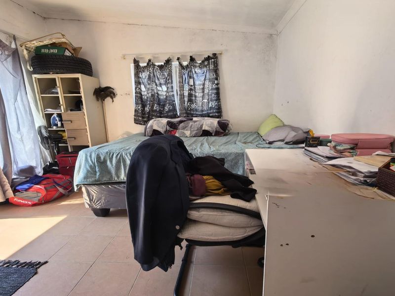 A bedroom featuring tiled flooring and a sliding glass door, currently requiring maintenance and cosmetic updates to the walls.