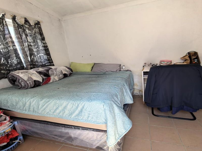A bedroom featuring tiled flooring and a window, currently showing signs of wall wear and staining that would benefit from cosmetic updates.