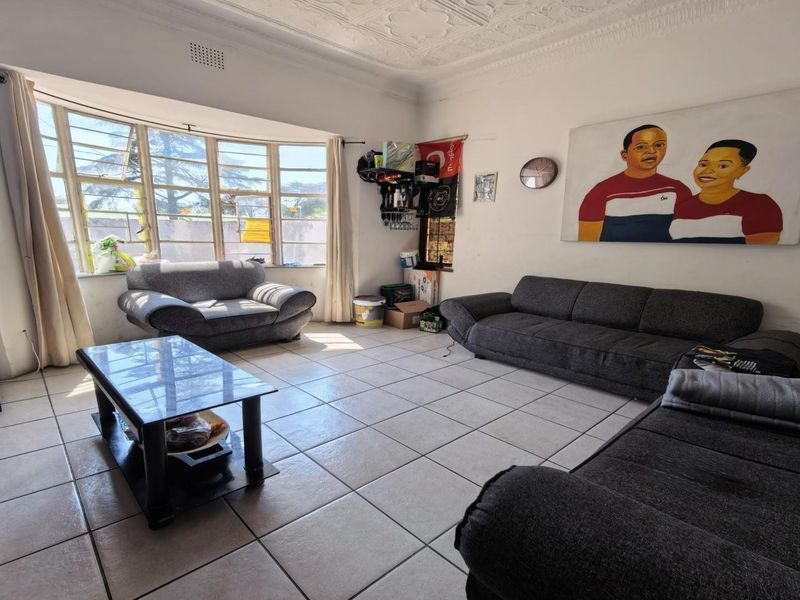 Spacious living room featuring large bay windows, tiled flooring, and a decorative pressed metal ceiling with ornate cornicing.
