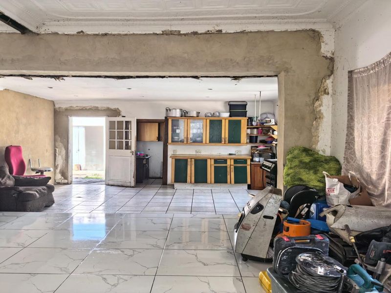 Open plan living and kitchen area featuring tiled floors and built-in cabinetry, currently undergoing renovation with unfinished wall and ceiling surfaces.