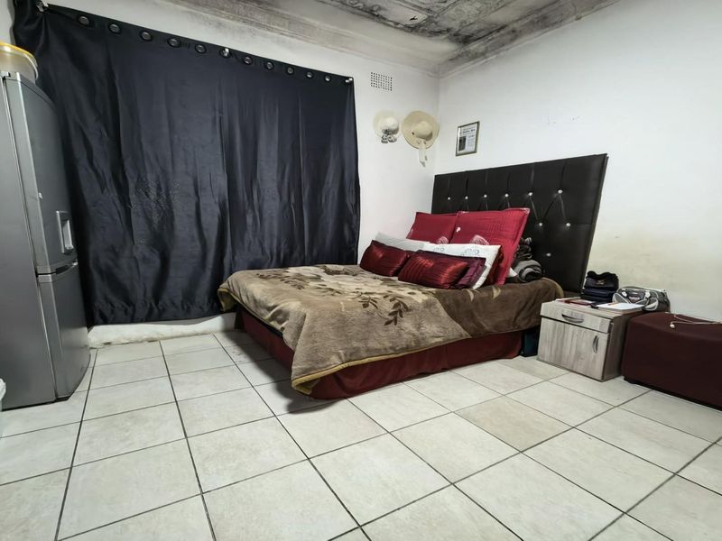 A bedroom featuring tiled flooring and significant ceiling and wall damage requiring maintenance and cosmetic repair.