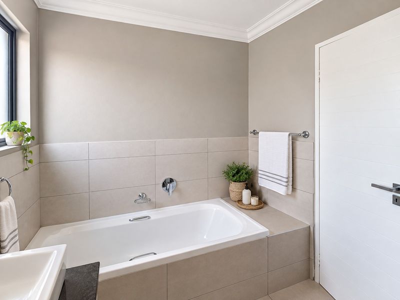 A modern, well-maintained bathroom featuring a built-in bathtub with chrome fixtures, neutral wall tiles, and clean finishes.