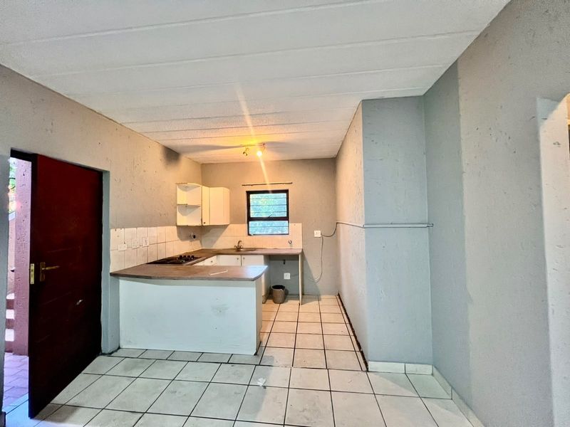 A compact, empty kitchen featuring built-in cabinetry, a hob, and tiled flooring, offering a blank canvas for renovation and modernization.