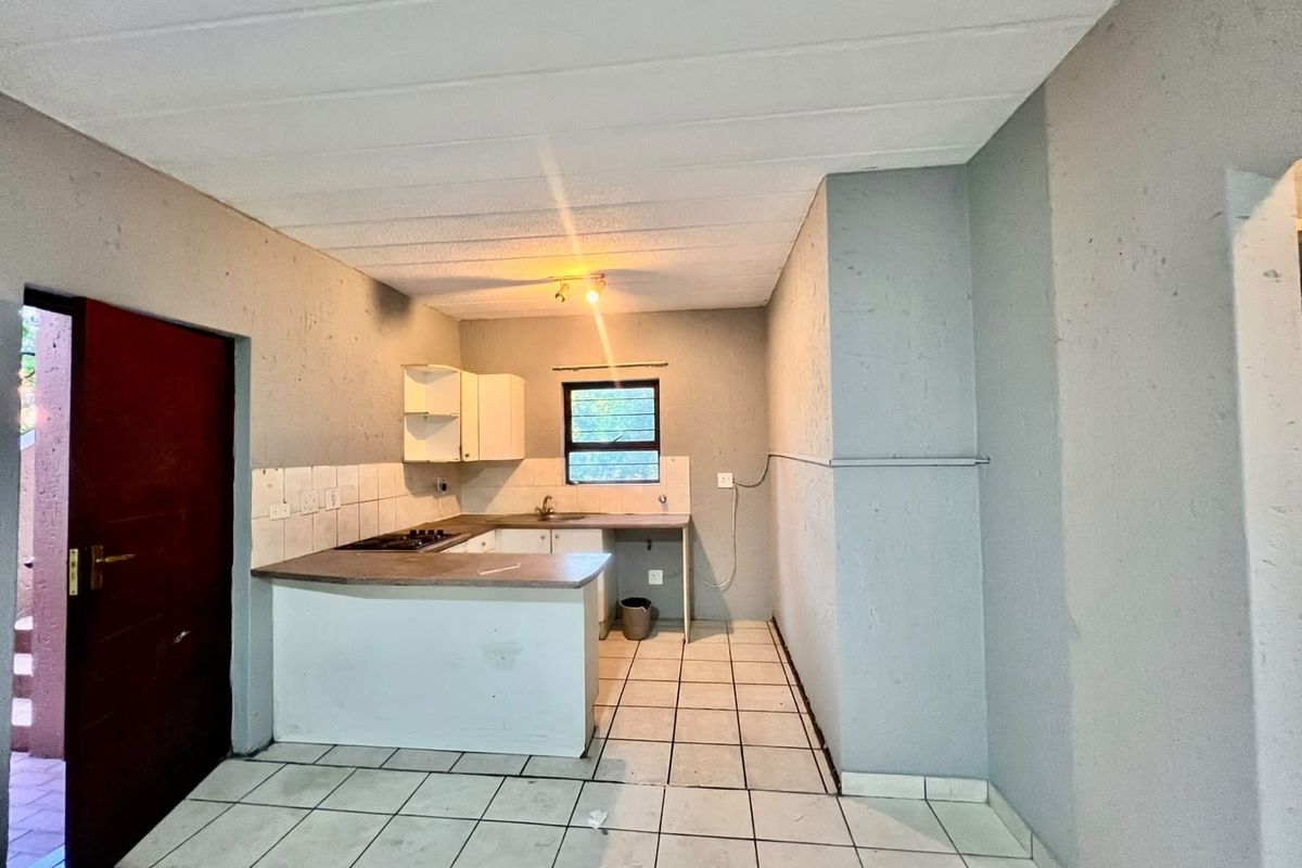 A compact, empty kitchen featuring built-in cabinetry, a hob, and tiled flooring, offering a blank canvas for renovation and modernization.