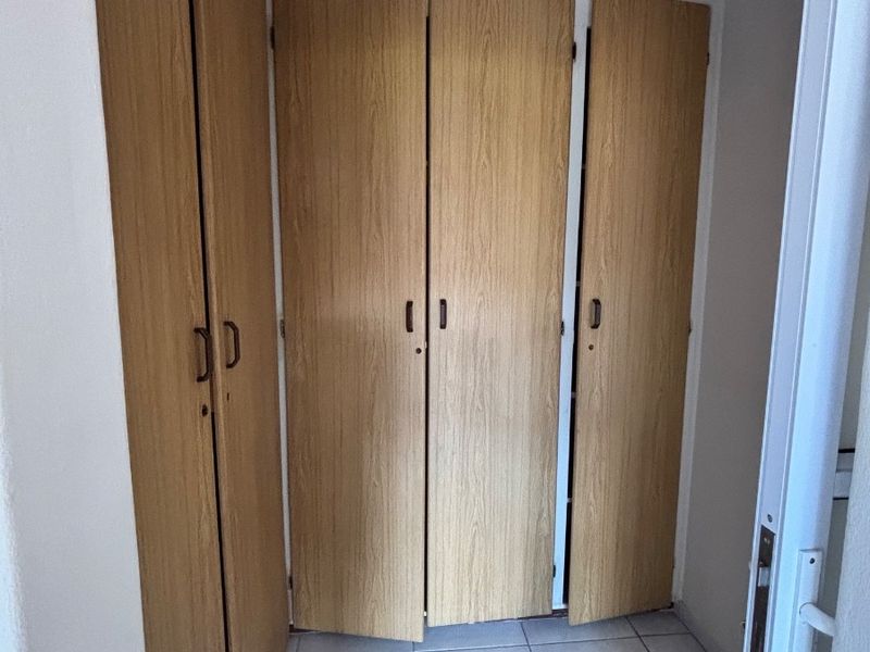 A hallway featuring built-in wooden cupboards and tiled flooring, providing functional storage space within the townhouse.